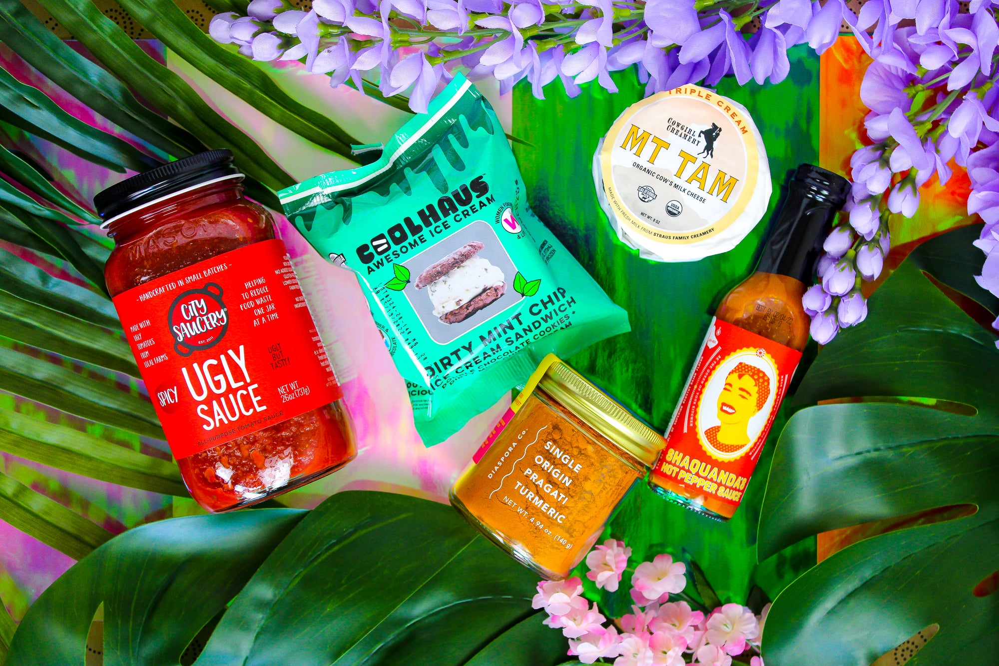 Products by queer and LGBT producers. From left to right: City Saucery Ugly Sauce, Coolhaus "Dirty Mint" Ice Cream Sandwich, Diaspora Co Turmeric, Cowgirl Creamery Mt. Tam Cheese, Shaquanda's Hot Sauce.
